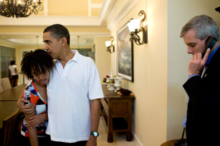 On vacation in Hawaii on Dec. 29, 2009, President Barack Obama hugs his daughter Malia while National Security Council Chief of Staff Denis McDonough waits to connect him on the latest conference call following an attempted Christmas Day terrorist attack.Official White House photo by Pete Souza